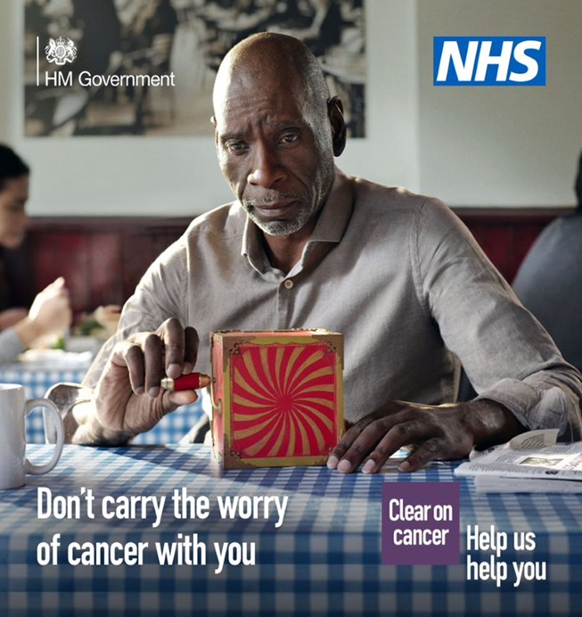 A middle-aged person sitting a cafe with a red jack-in-the-box toy on the table across from them. The person is looking at the red-jack-in-the-box with a concerned expression on their face. The text reads: Don’t carry the worry of cancer with you. The NHS logo is in the top right hand corner